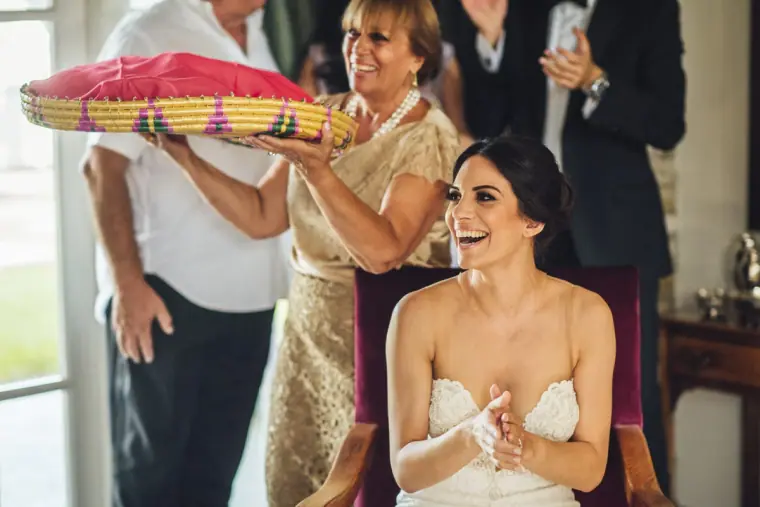 Ruby laughing as a relative lifts a woven tray over her head in the Cypriot tradition