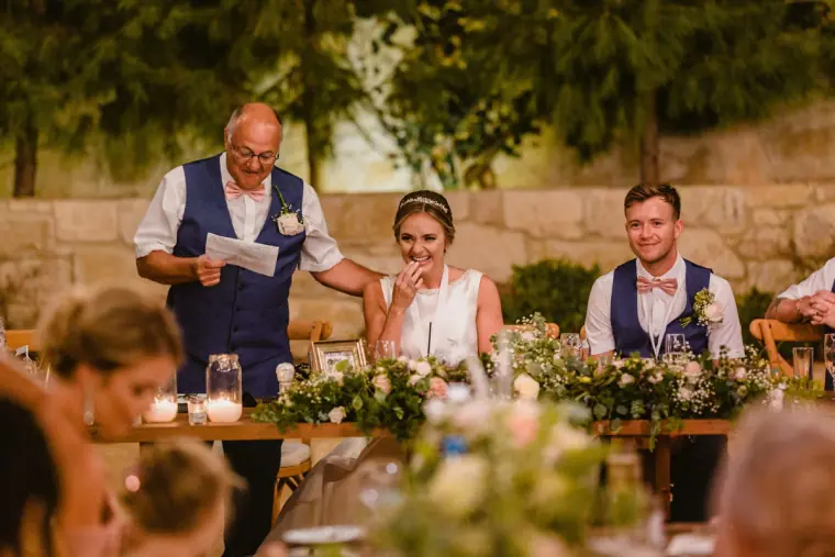 Bride's father reading his speech as the bride wipes away a tear