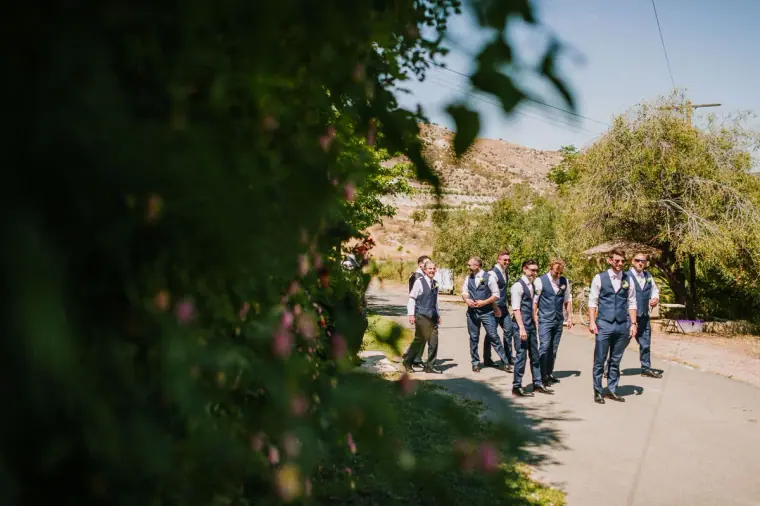 Groom and groomsmen walking up a sunny country lane towards the venue