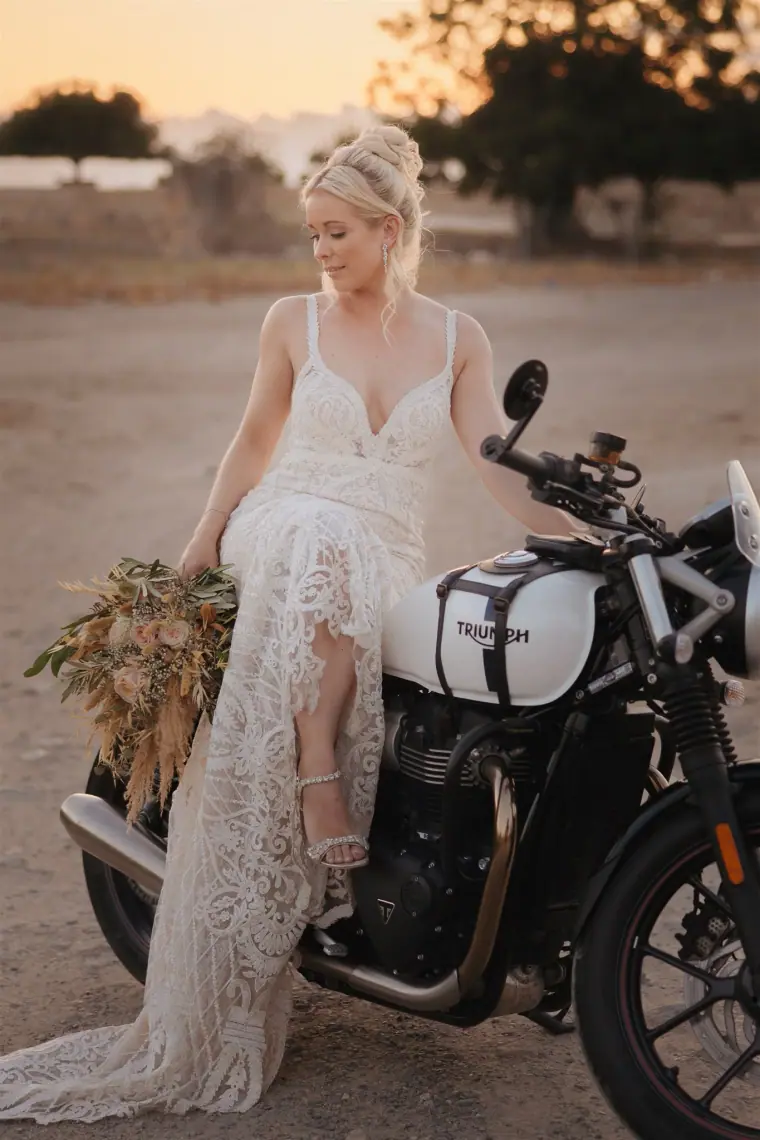 Bride perched on a motorbike in golden evening light