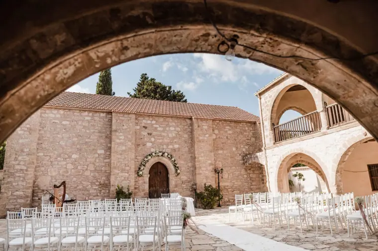 Ceremony chairs set out in the monastery courtyard, framed by a stone arch at Minthis Hills