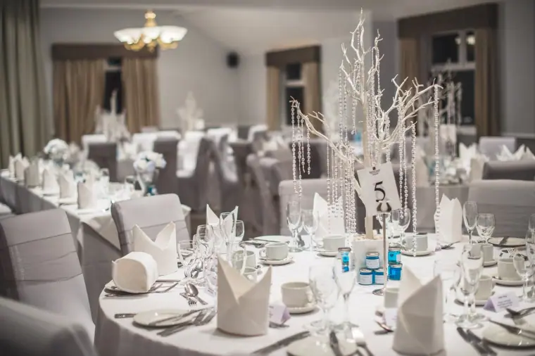 Reception tables with white linen and white branch centrepieces hung with crystals