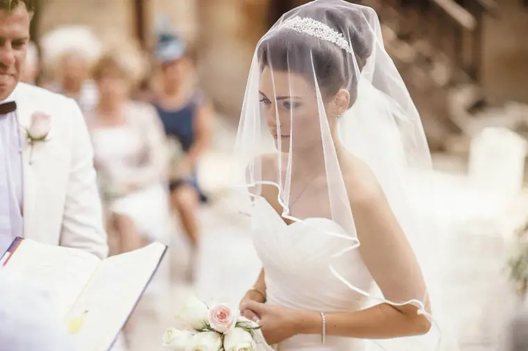 Bride looking down beneath her sheer veil during the ceremony