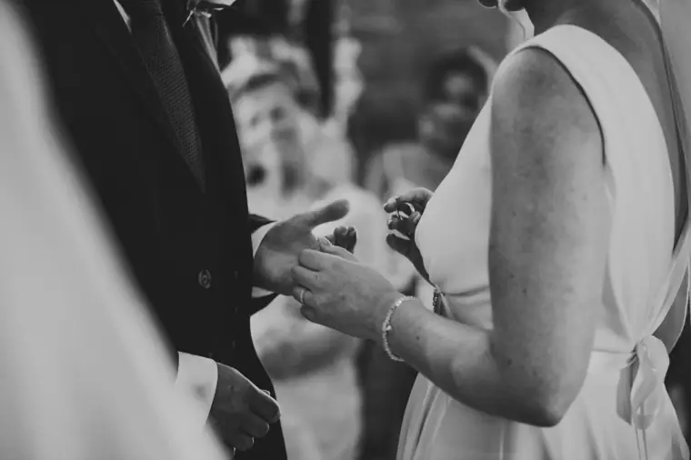 Black-and-white close-up of the bride placing a ring on the groom's finger