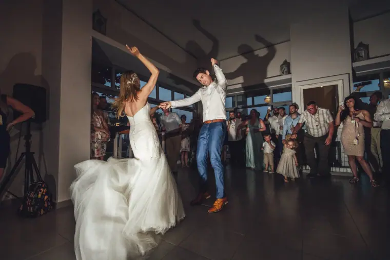 Bride twirling her skirt on the dance floor as the groom dances among guests