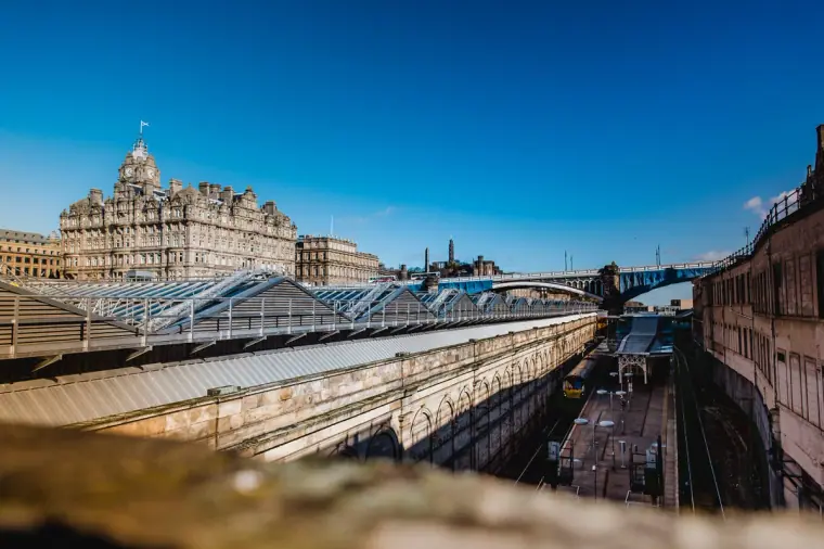 Waverley Station's glass roof with the Balmoral Hotel beyond under blue sky, Edinburgh