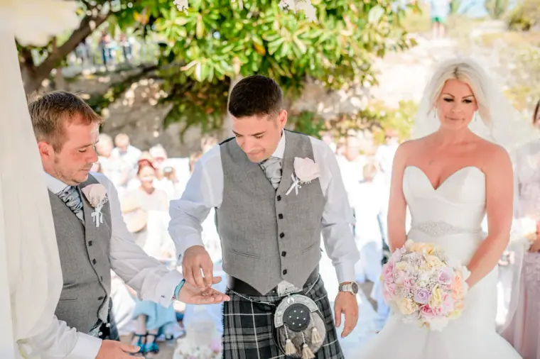 Groom laughing as he slides on the ring beside the smiling bride