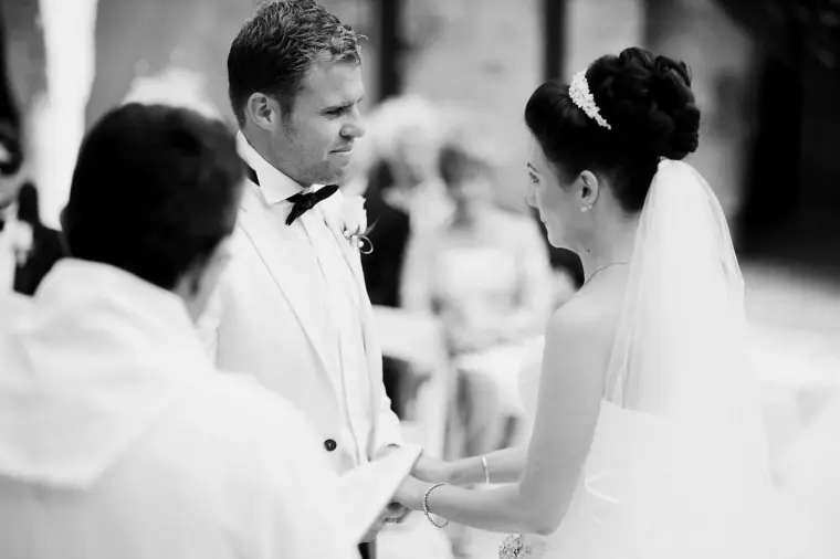 Black-and-white shot of the couple holding hands as they exchange vows