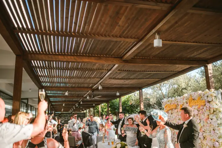 Guests raising glasses beneath the slatted terrace roof during the reception at Almyra
