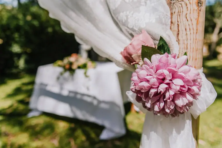 Pink dahlia and lace tied to the ceremony arch post