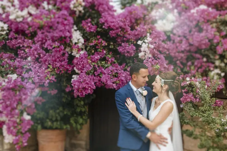 Donna and Byron embracing in front of a wall of pink bougainvillea