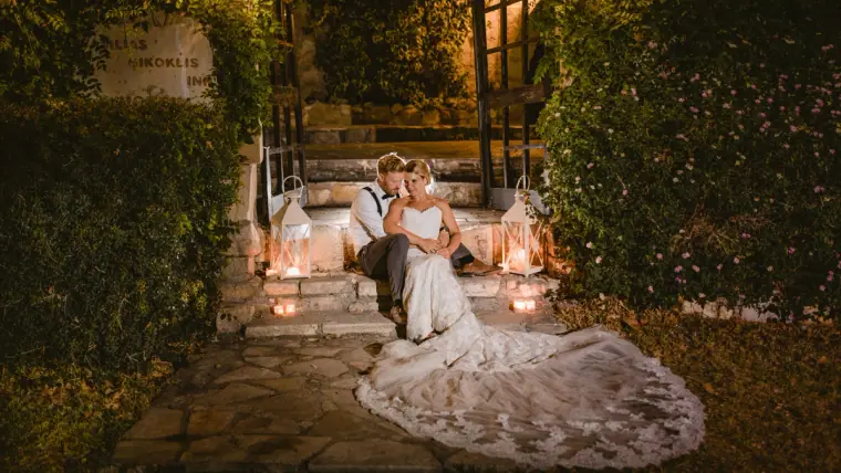 Bride sitting on lantern-lit stone steps, her lace train fanned out around her