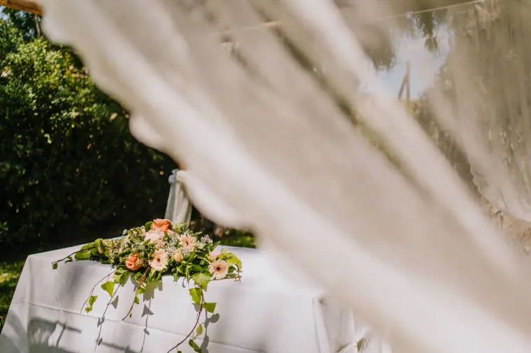 Peach and pink floral arrangement on the signing table, seen through lace drapes