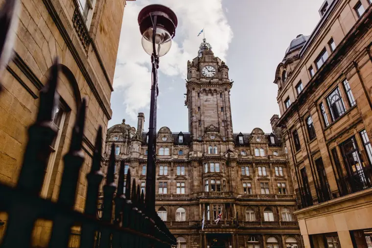 Balmoral Hotel clock tower framed by Victorian buildings and a lamp post, Edinburgh