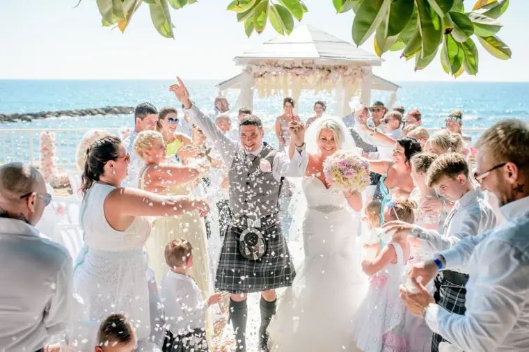 Guests showering the newlyweds with confetti in front of the gazebo by the sea