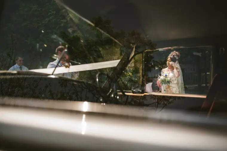 Bride glimpsed through the windscreen of a classic car