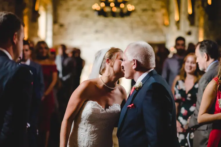 Father kissing the bride at the end of the aisle