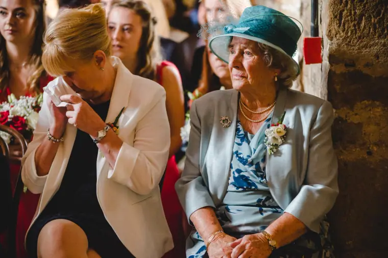 Two women overcome with emotion during the ceremony, one in a blue hat