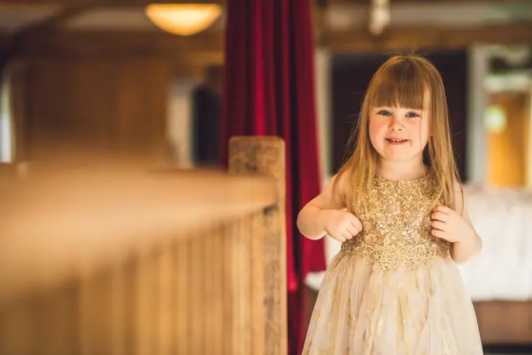 Flower girl in a gold sequin dress smiling on the landing
