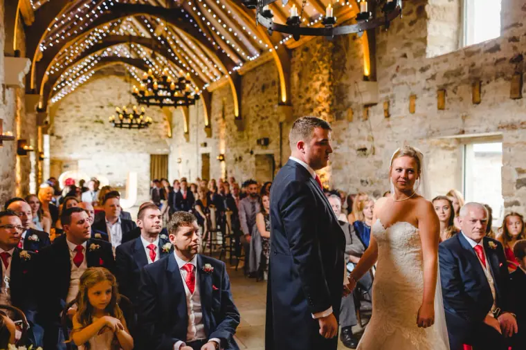 Sonny and Jo facing each other at the front of the beamed ceremony hall