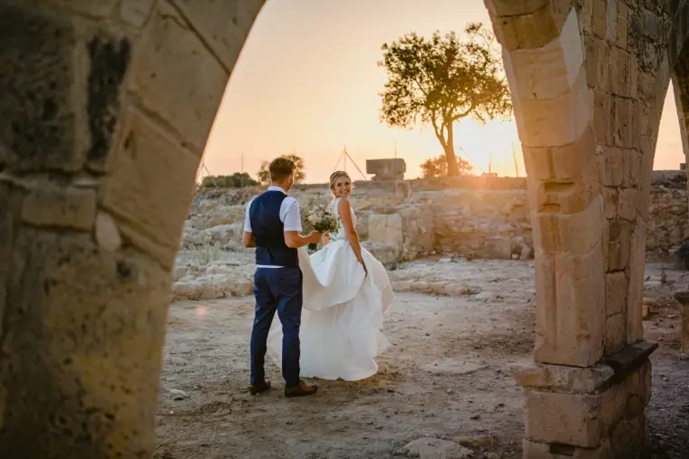 Couple framed by a weathered stone arch in warm sunset light near Kouklia