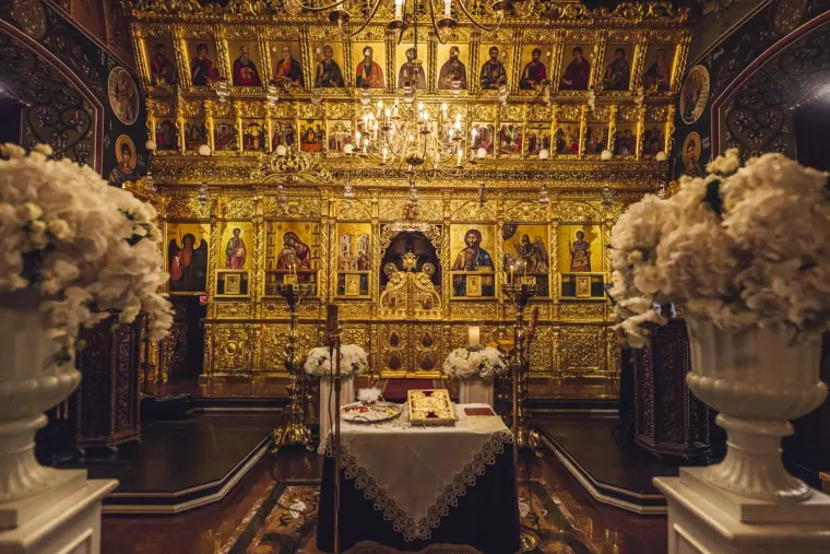 Golden iconostasis and white flowers at the altar of the Orthodox church