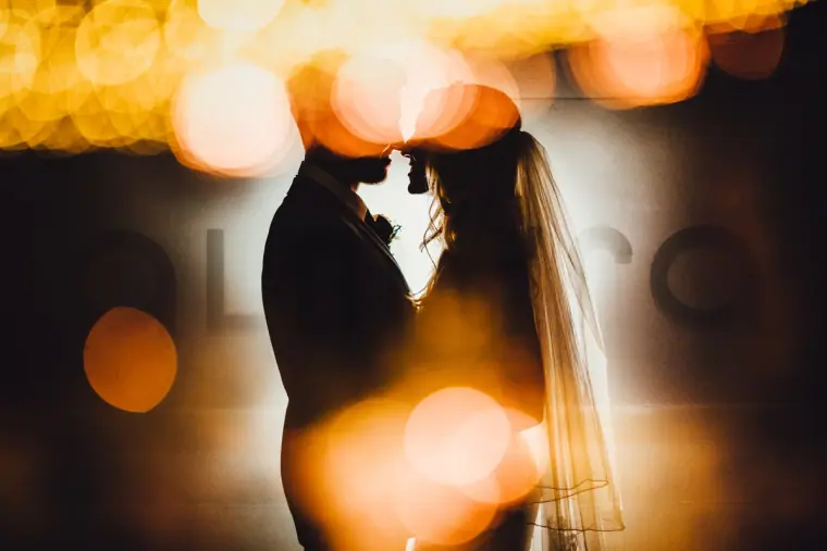 Silhouette of a couple face to face among golden bokeh lights