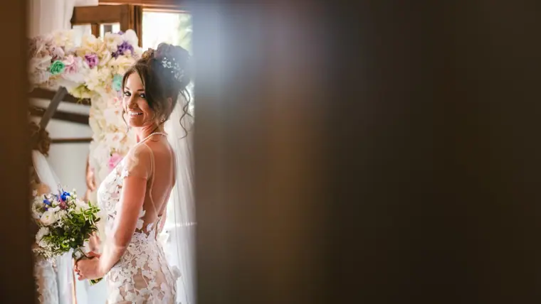 Bride with a white and purple bouquet glancing back in a doorway