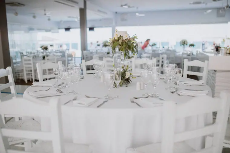 Reception room with round tables, white chairs and green and white centrepieces