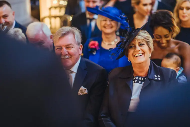 Smiling guests in hats and suits waiting for the ceremony to begin