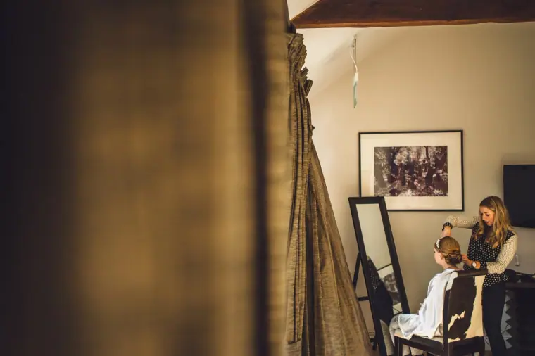 Bride getting ready in a room with a framed photo, glimpsed through a curtain