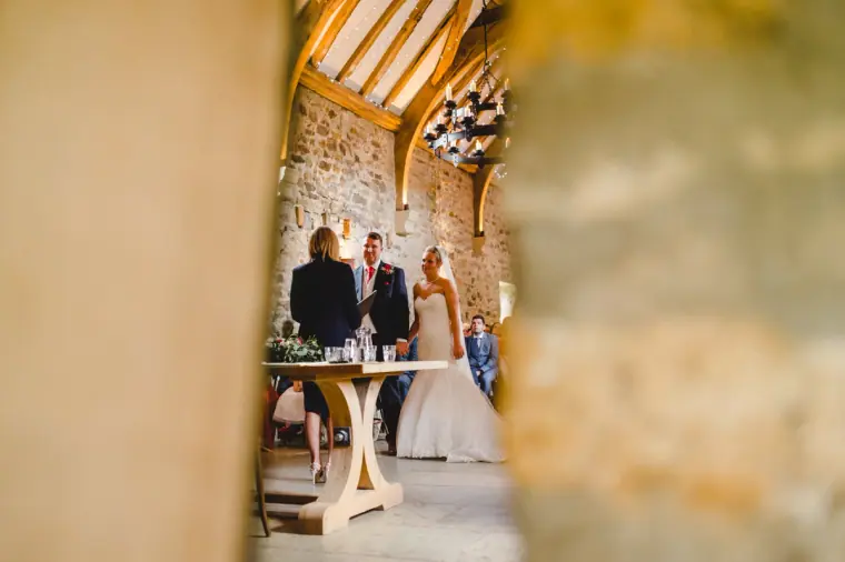 Couple signing the register, glimpsed through a gap in the stone wall