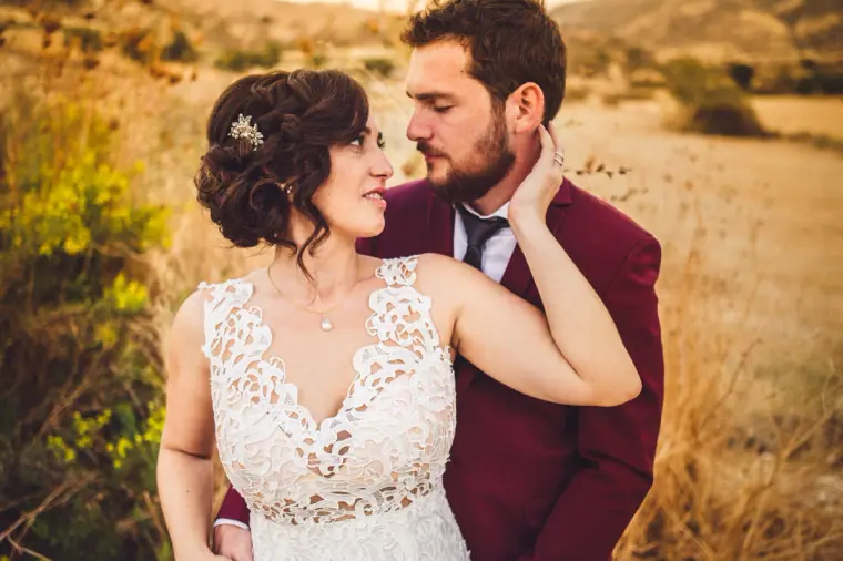Close embrace of the bride and groom against sunlit golden fields