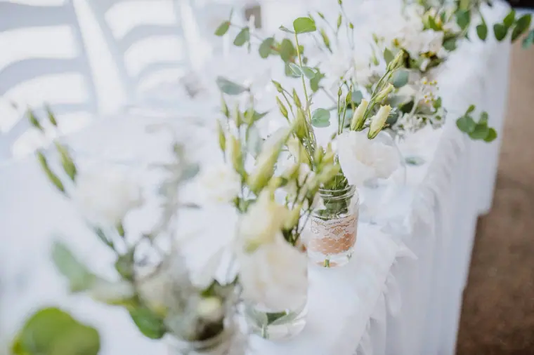 Top table lined with white flowers and eucalyptus in small vases