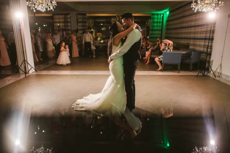 Jaclyn and Steven's first dance in a spotlit reception room as guests watch