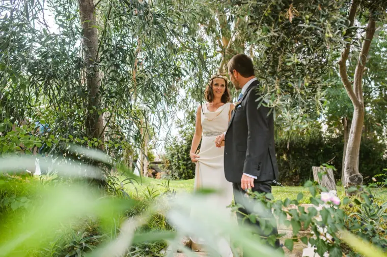 Bride and groom standing together among tall trees in the garden