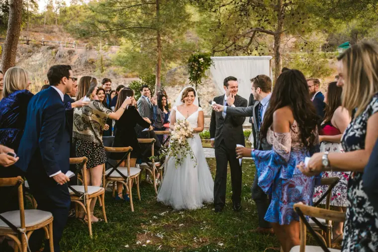 Guests applauding as the newlyweds walk back up the grassy aisle