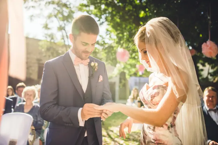 Groom placing the ring on the bride's finger in the garden ceremony