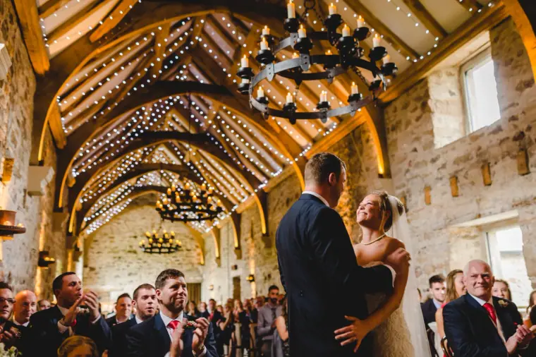Sonny and Jo embracing beneath the fairy-lit beams as guests applaud