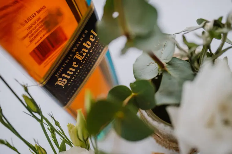 Bottle of Johnnie Walker Blue Label among eucalyptus and white flowers