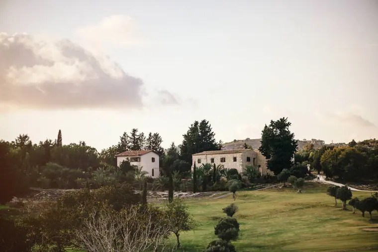 Rolling lawns and stone houses among trees at Minthis Hills, Paphos