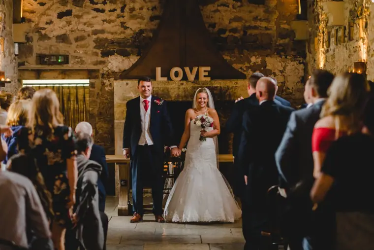 Couple at the front of the hall beneath a LOVE sign during the ceremony