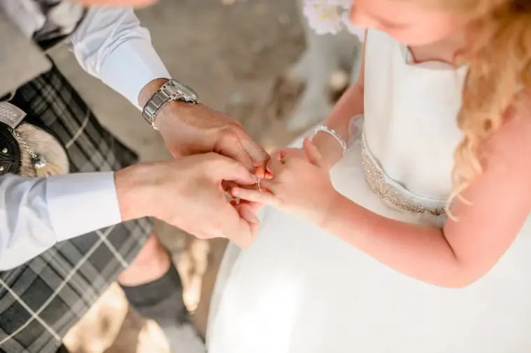 Groom placing a ring on the flower girl's finger