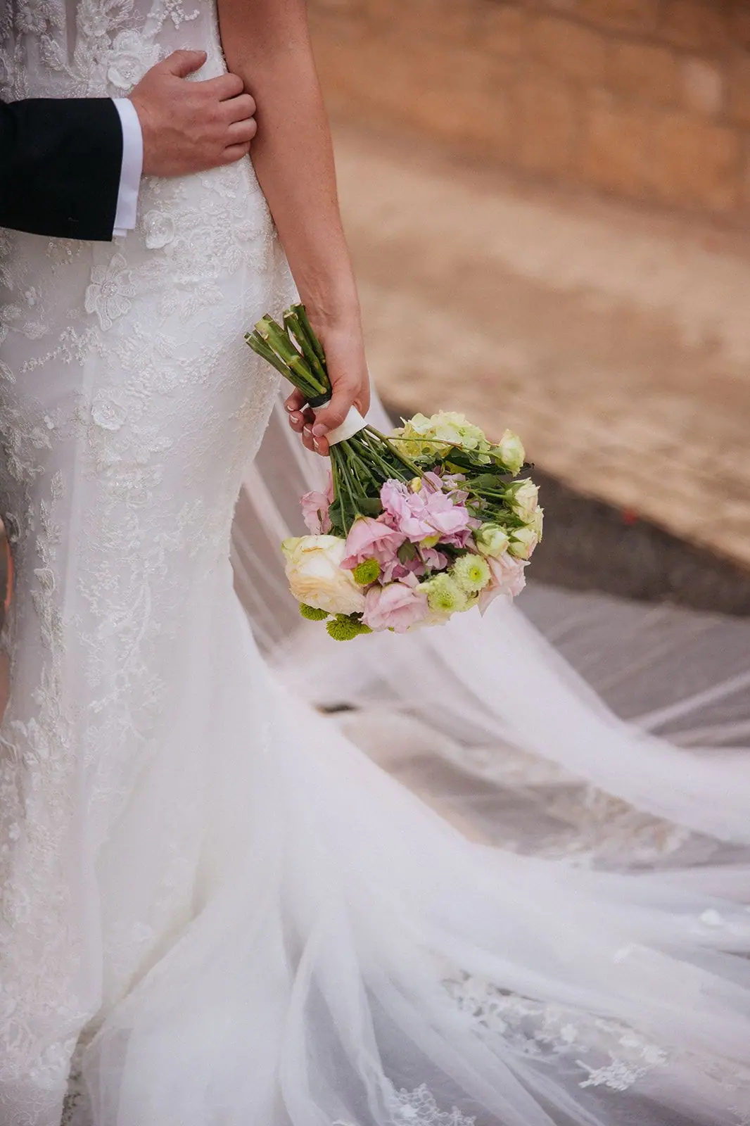 Close-up of Zoe's bouquet and lace train as she walks