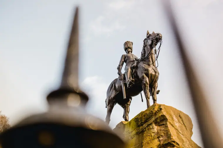 Royal Scots Greys equestrian statue framed by blurred railing spikes, Princes Street