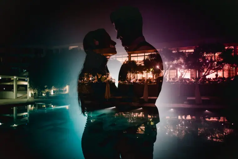 Double exposure of Jaclyn and Steven's silhouettes over the hotel pool lit at night