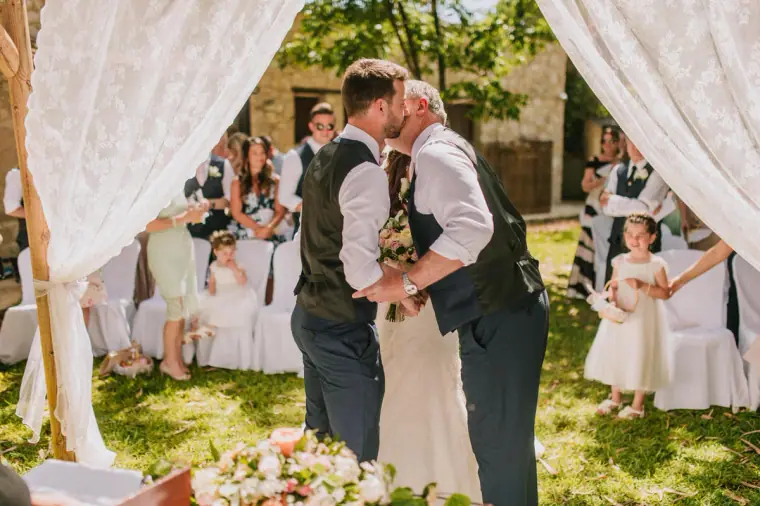 Claire's father kissing Sean's cheek as he hands over the bride at the arch