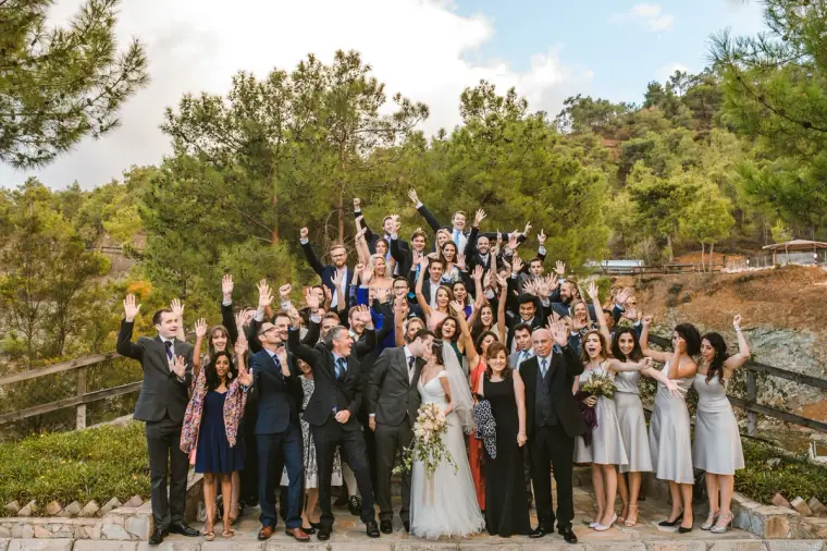 Large group photo of cheering guests on the steps among pine trees at Lexeko Estate