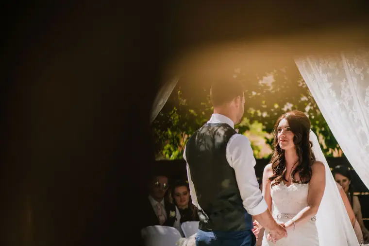 Sean and Claire facing each other at the lace-draped ceremony arch