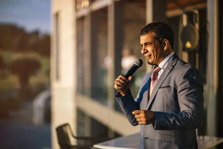 Guest in a grey suit giving a speech into a microphone at the reception